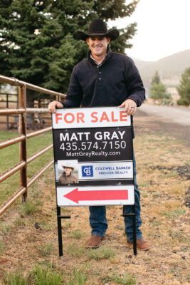 Matt Gray helps with selling a home by placing a for sale sign on a property.